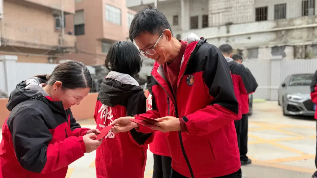 Padmat Rubber employees in red jackets sharing lucky red envelopes at factory yard