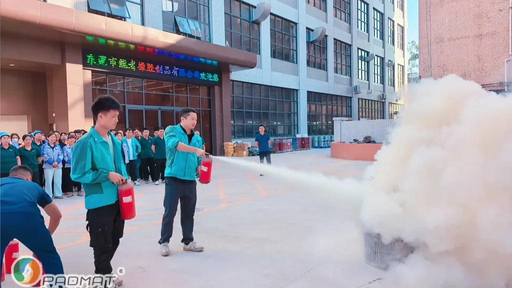 Fire drill at Padmat Rubber factory with workers using fire extinguishers and observing safety training