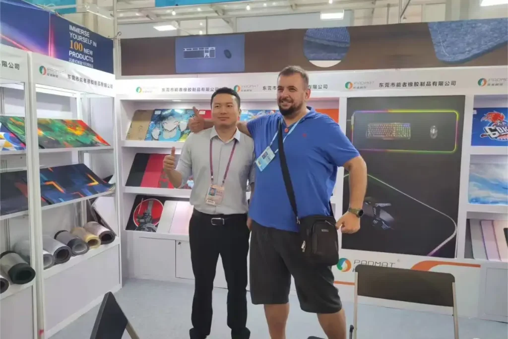 Padmat Rubber mousepad factory exhibition booth with German customer and factory representative, showcasing custom gaming mousepads and RGB desk mats