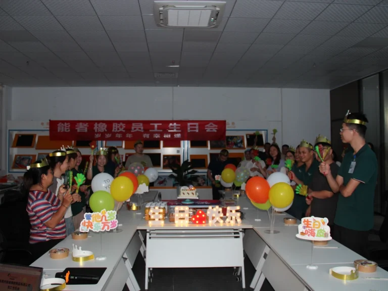 Office quarterly birthday celebration, lit candles on cake, employees with golden birthday crowns making birthday wishes collectively