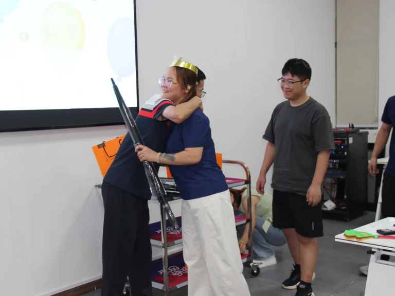 Birthday party scene, Chairman Zhou Yu hands out gifts and warmly hugs employee wearing golden birthday crown