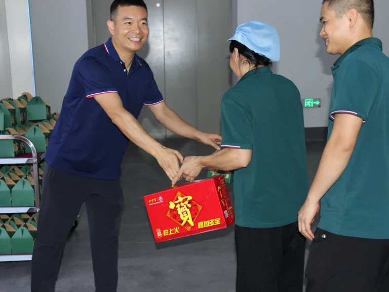 Factory director with warm smile hands over festival gift box to employee during Patmat Dragon Boat Festival benefit distribution