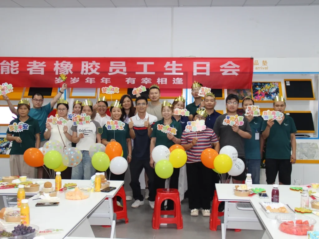 Group photo of all birthday staff at Patmat Rubber quarterly birthday party, everyone wears golden birthday crowns, holding birthday gifts under theme red banner