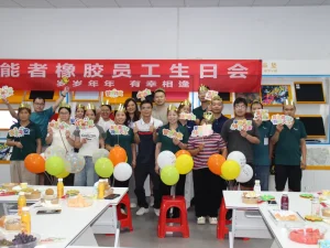 Group photo of all birthday staff at Patmat Rubber quarterly birthday party, everyone wears golden birthday crowns, holding birthday gifts under theme red banner