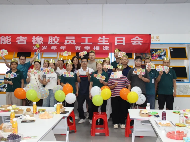 Group photo of all birthday staff at Patmat Rubber quarterly birthday party, everyone wears golden birthday crowns, holding birthday gifts under theme red banner