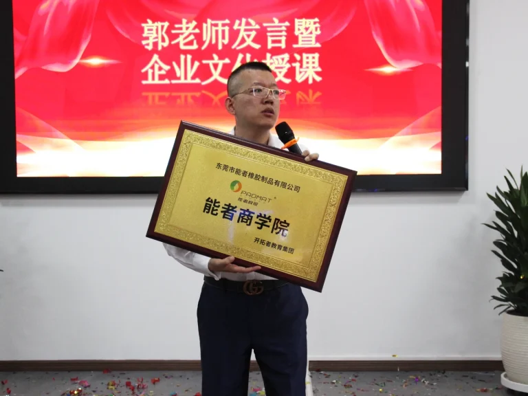 Lecturer Guo Dayin from Kaituo Education Group holding the padmat rubber Business School plaque and speaking at the launch ceremony.