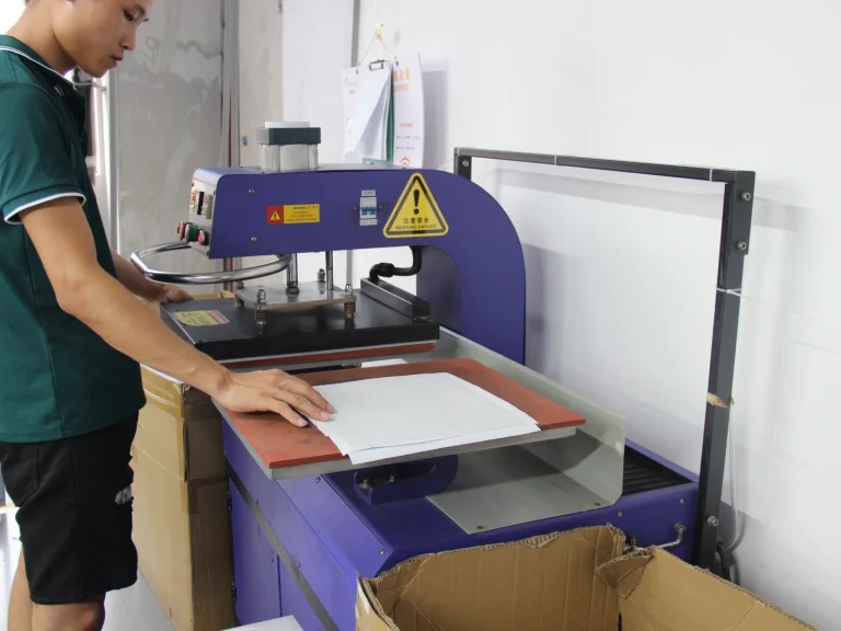 Worker operates heat transfer equipment in production workshop to transfer customized patterns onto mouse pad fabric